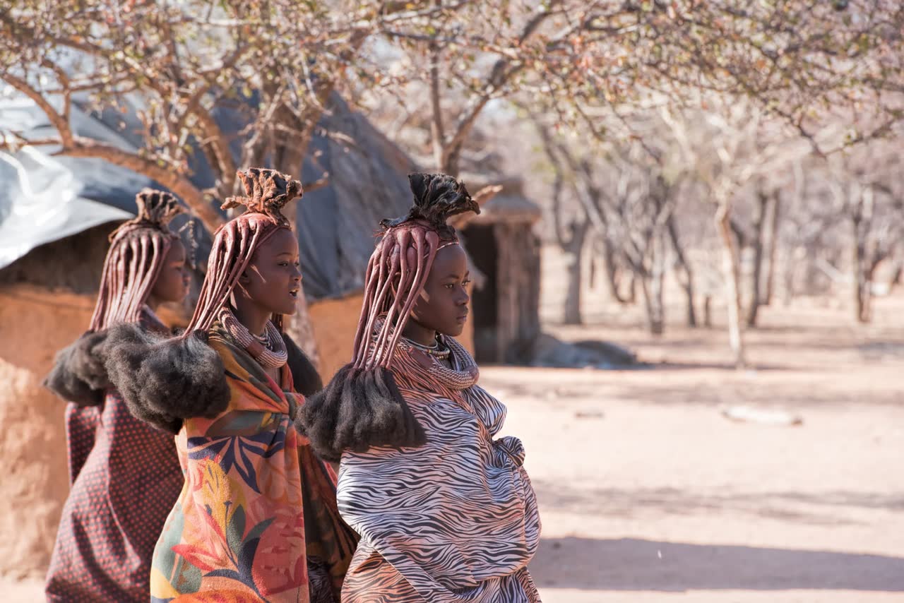 Himba women in traditional dress at a homestead in the Kaokoveld, Namibia