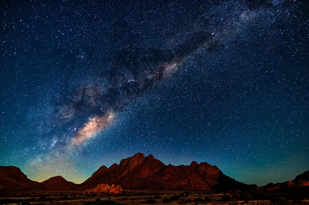 The Milky Way arching over granite peaks in the Namibian desert at night